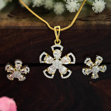 Gold-tone jewelry set featuring a cross-shaped pendant necklace, matching stud earrings, and a chain, decorated with clear rhinestones, displayed on a dark wooden surface with white and pink flowers.